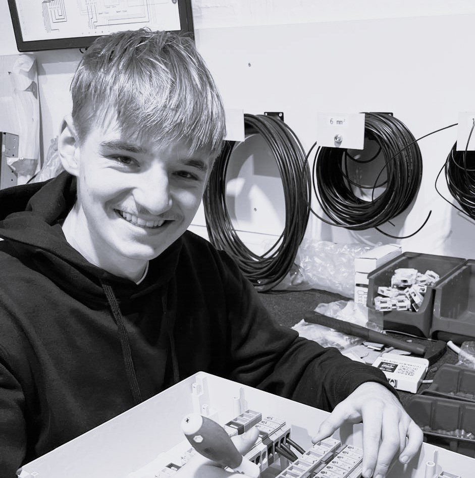 Auszubildender bei Bergisch Solar wird bei der Arbeit fotografiert und lächelt in die Kamera in Schwarz und weiß.